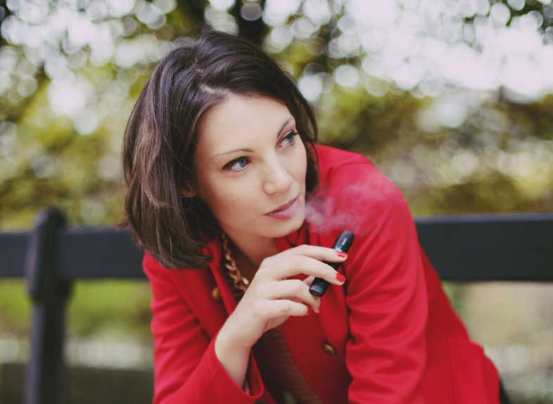 Chica fuma tranquilamente cigarrillo electrónico