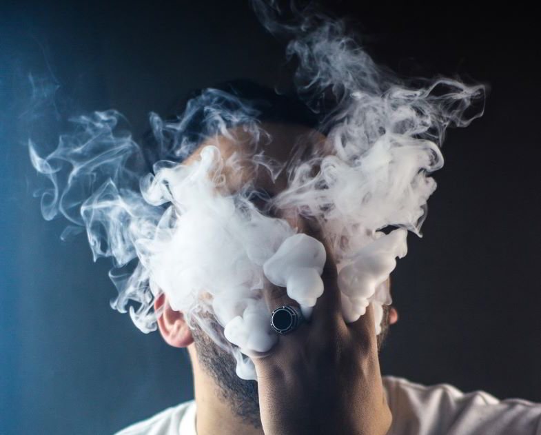 Niño exhalando el vapor de un cigarrillo electrónico de pulmón