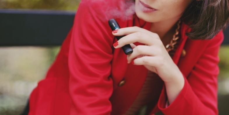 Mujer vapeando con un cigarrillo electrónico compacto