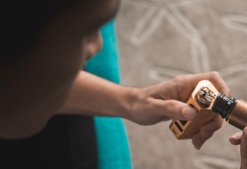 Persona vertiendo un líquido premezclado en su cigarrillo electrónico