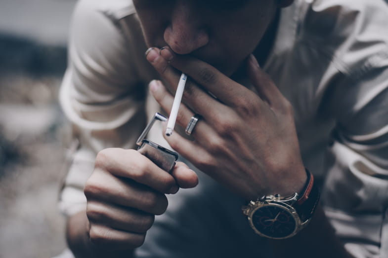 Niño adicto a la nicotina encendiendo un cigarrillo
